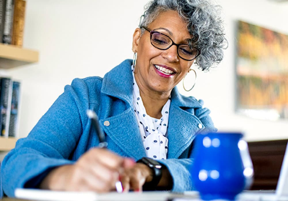 A beautiful mature black woman with gray hair working from home.
